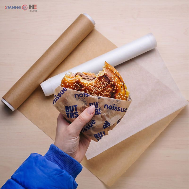 Burger wrapped in printable greaseproof paper next to kraft and white rolls