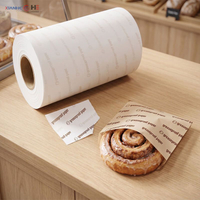 Compact roll of greaseproof paper formatted as a dispenser roll, commonly known as a greaseproof paper toilet roll, next to a wrapped pastry
