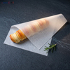 Plain white greaseproof paper sheet wrapped around a baked pastry on a slate board