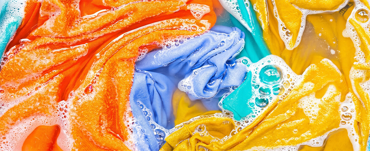 Colorful sublimated garments soaking in soapy water to test ink color fastness and migration.