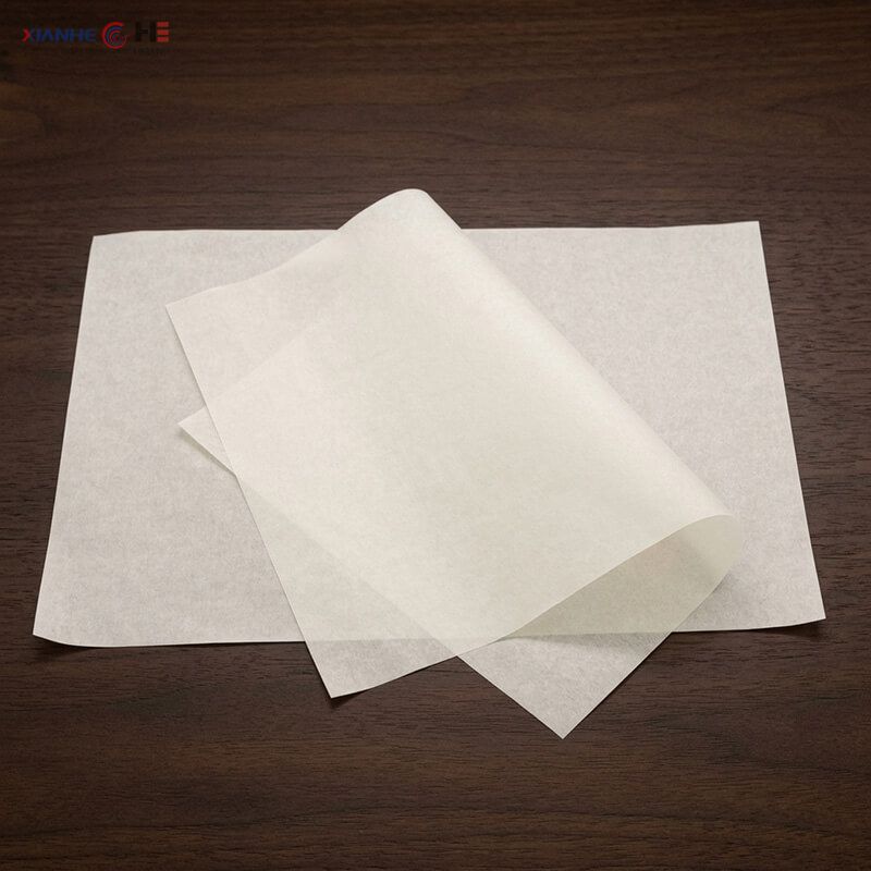 Pre-cut flat unprinted greaseproof paper sheets showing smooth surface on a wooden table