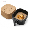 Pre-cut square air fryer baking paper sheets with ventilation holes in an air fryer basket cooking french fries
