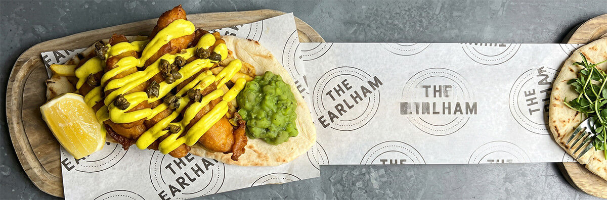 Continuous food-grade greaseproof paper roll with custom brand printing, showing excellent moisture and oil resistance under heavy sauces and fried fish.