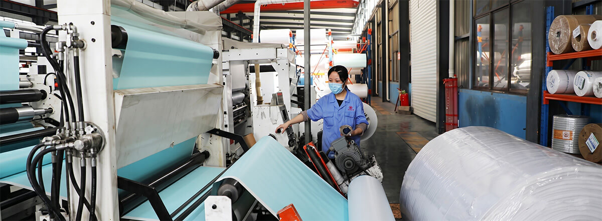 Factory worker conducting quality control on a sublimation paper production line.