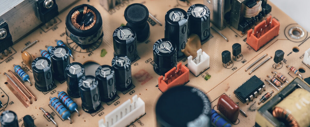 Radial aluminum electrolytic capacitors mounted on a power supply circuit board showing polarity markings