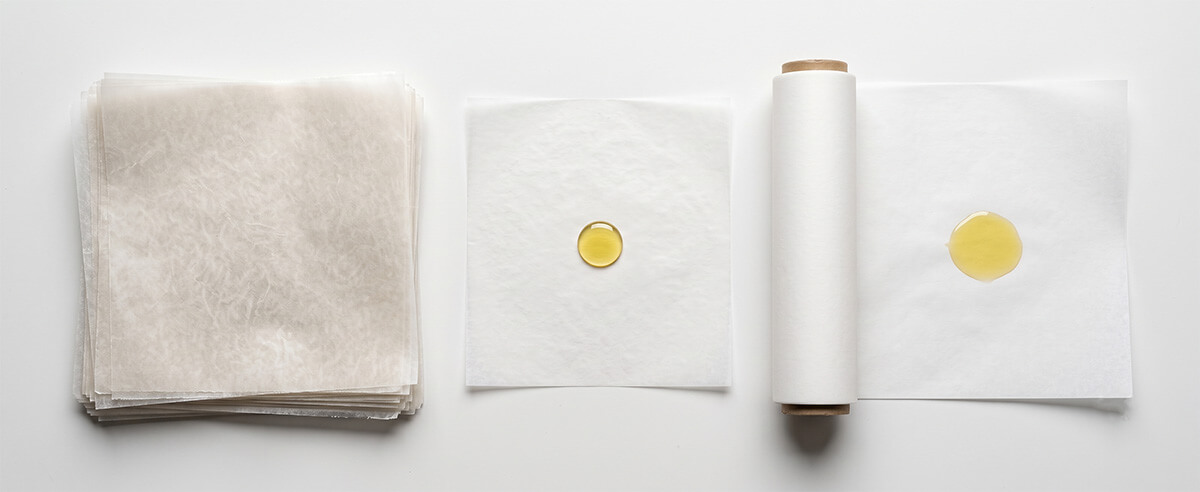 Glassine greaseproof paper compared side by side with silicone-coated parchment paper, showing oil resistance difference