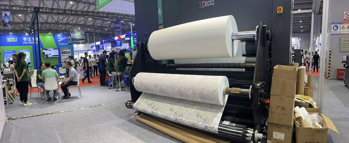 Heavy-duty unwind system feeding an industrial sublimation paper jumbo roll on a wide-format textile printer